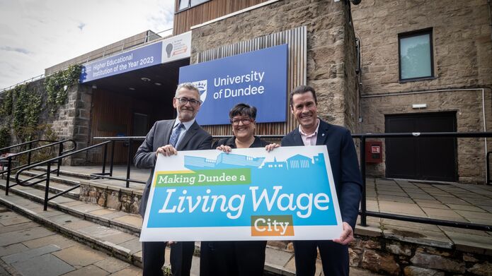 Professor Shane O'Neill, Councillor Lynne Short and Dr Jim McGeorge outside of the University's Tower Building with a sign to promote Dundee as a Living Wage city