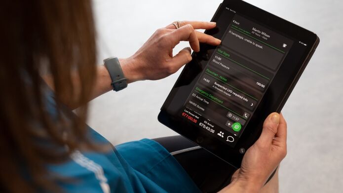 A woman using an iPad to check her blood pressure.