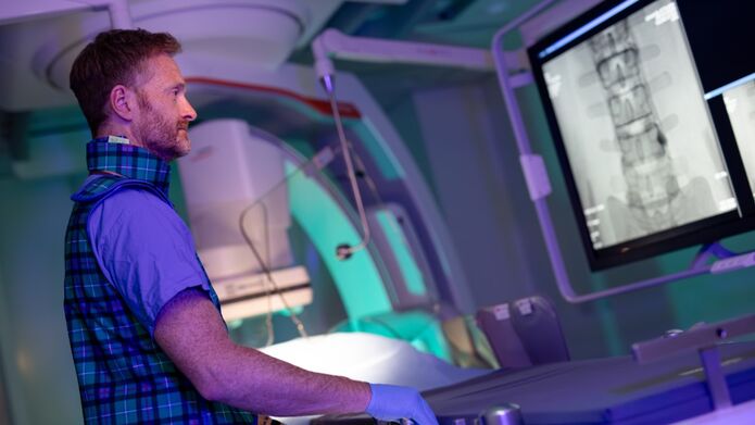 A man in a plaid shirt focused on a computer screen.