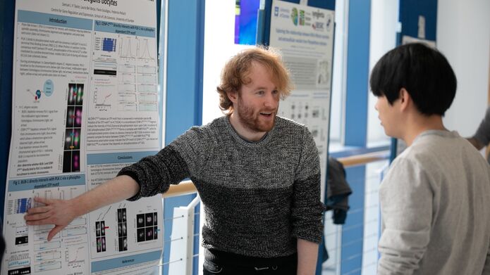 student showing research poster to a member of a staff
