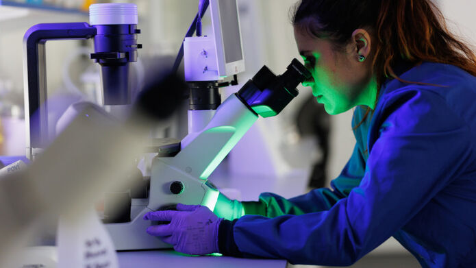woman looking into microscope