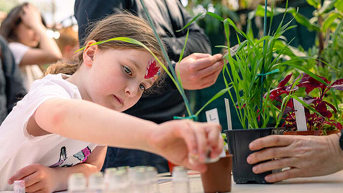 A young person looking at plants on a table at the Botanic Garden
