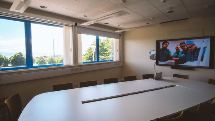 A conference room featuring a large screen at the front and several chairs arranged for attendees.