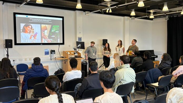 A diverse group of people in chairs, attentively listening to a speaker in a conference room