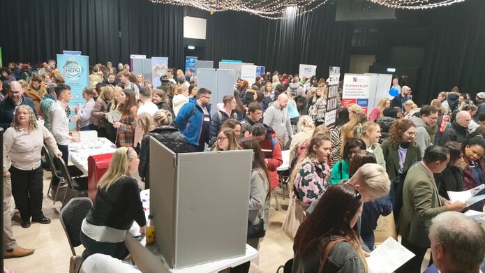 A bustling room of attendees visiting multiple stalls at the nursing fair