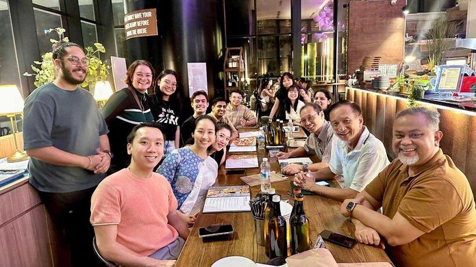 A group of people are sitting round a table in a restaurant, all looking in the same direction