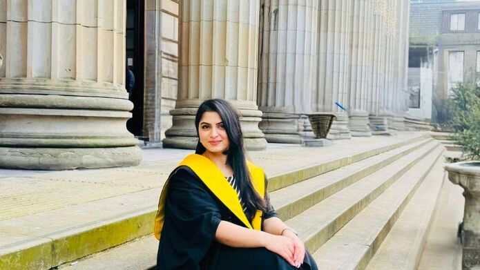 student in graduation robes sitting on steps