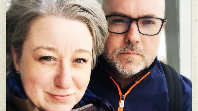 Woman with short grey hair standing in front of man