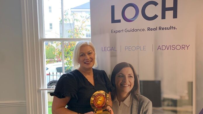 two women standing in front of banner advertising 'Loch'