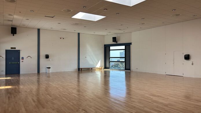 A large studio with wooden flooring and a large window at the back of the room.