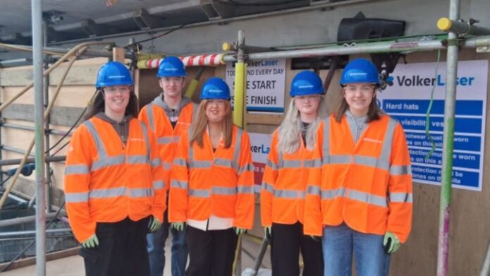 A group of students in hard hats and orange hi vis vests visiting Tay Bridge
