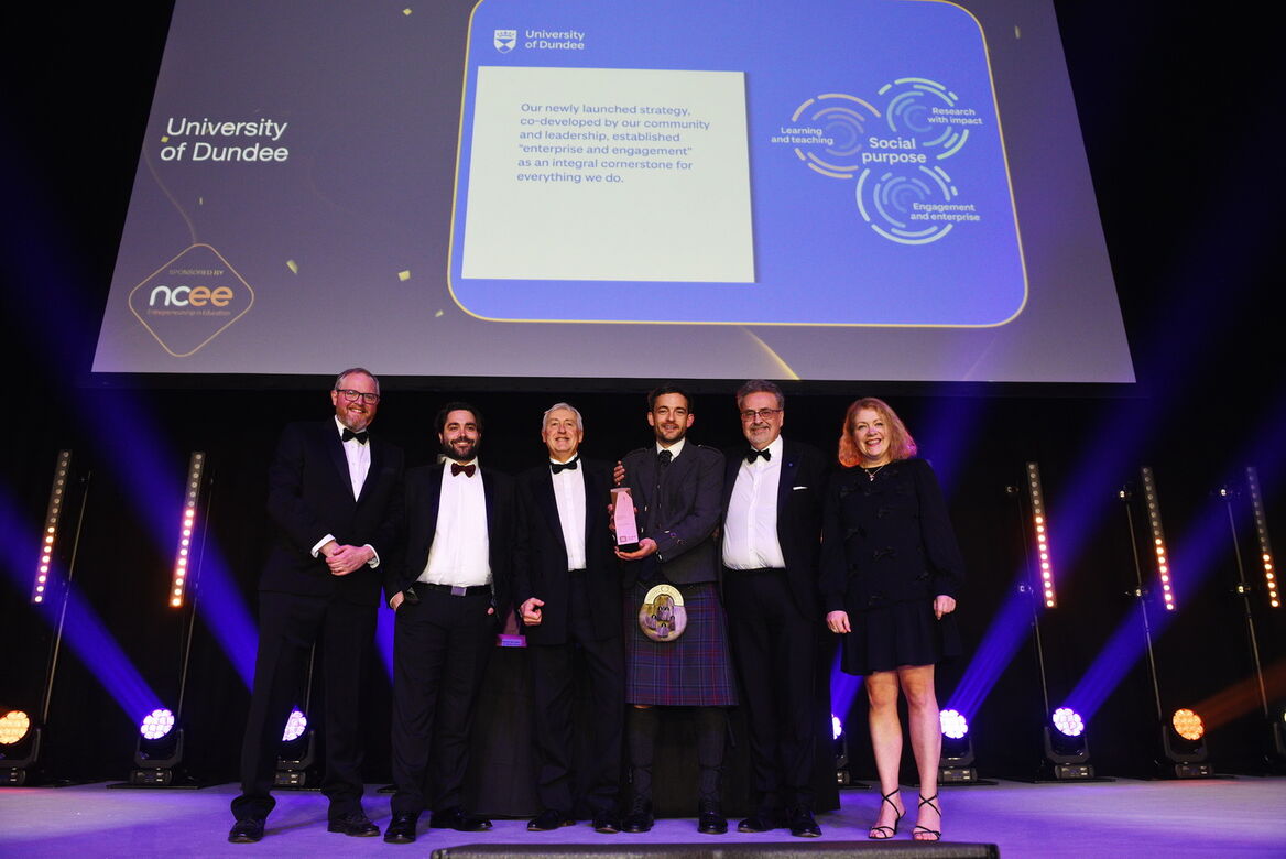 Men and women in formal wear stood on stage collecting an award