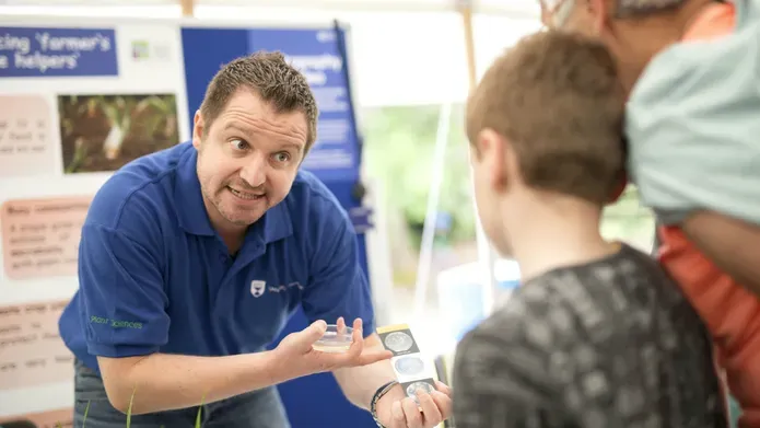 A man doing science communication to a child and adult