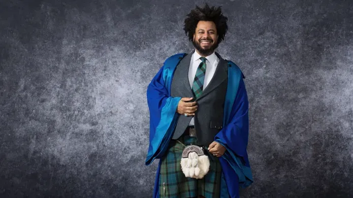 Johnathan Wilson in his graduation gown in front of a textured background