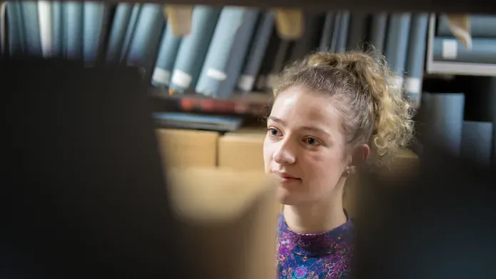 Girl looking at old books in an archive