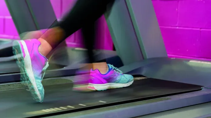 The feet of a person running on a treadmill with motion blur
