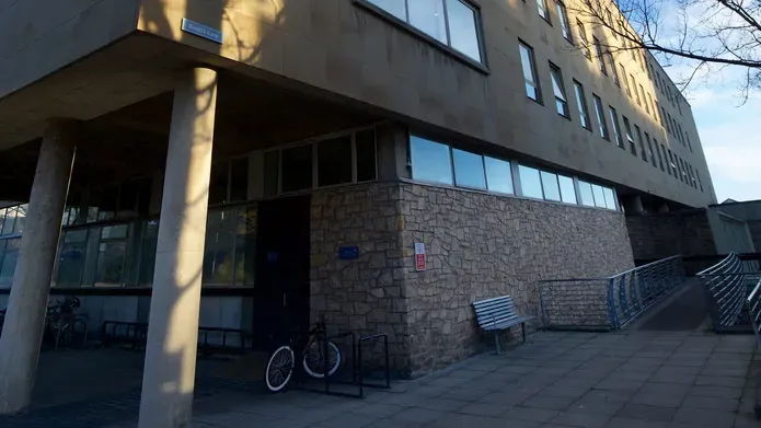 a building entrance with a ramp. There is also a bike and a bench