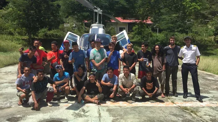 a group of people smiling in front of a helictopter
