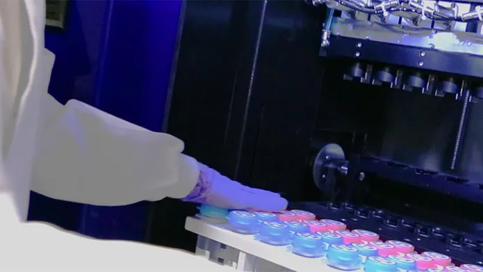 A person in PPE moving samples into or out of a fridge