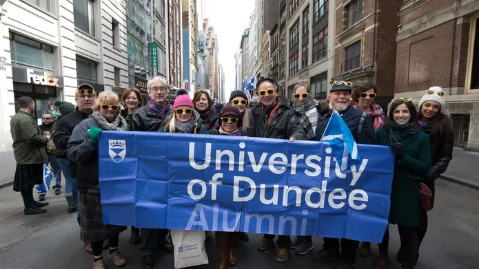 A group of people holding a University of Dundee banner