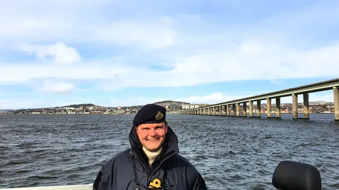 a photo of andy standing in front of a bridge