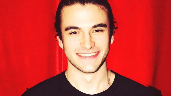 a headshot with a red background behind him