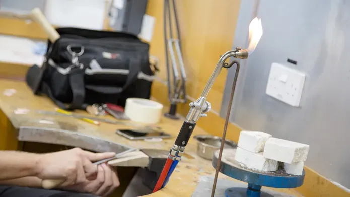 Hands working with a flame and blocks of material