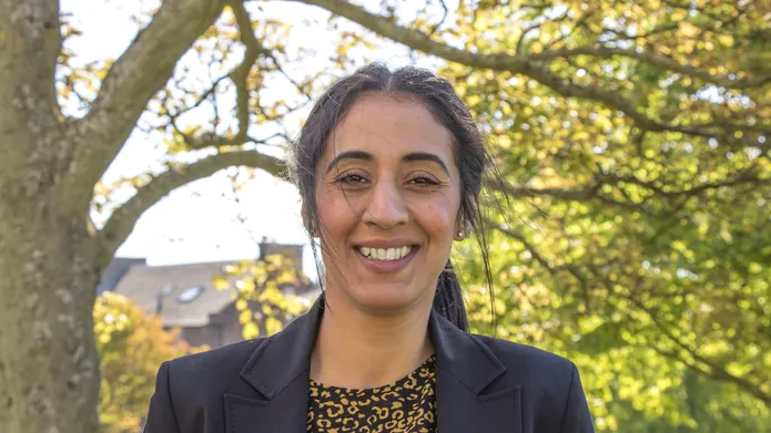 Norin Arshed standing smiling to the camera with a tree behind her