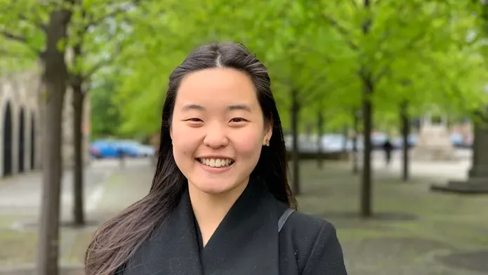 Wan Nee standing in front of green trees