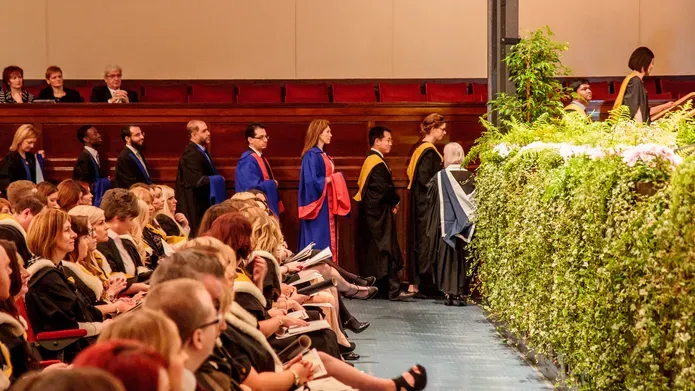 a queue of graduands at the side of the caird hall as they prepare to cross the stage