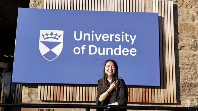 Jing Chen standing in front of the University of Dundee sign