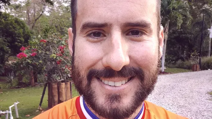 Alejandro smiling at camera wearing orange jumper