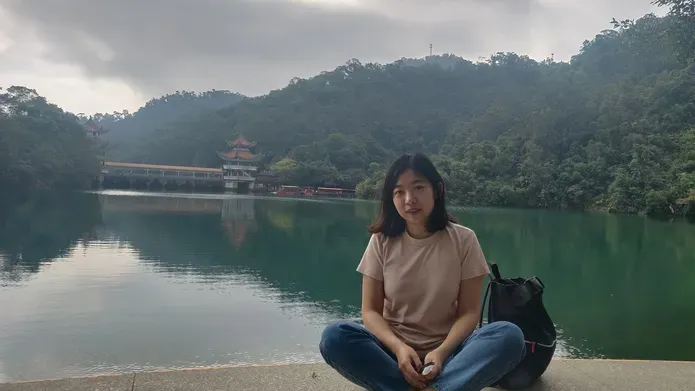 Ding Wang sitting in front of a lake