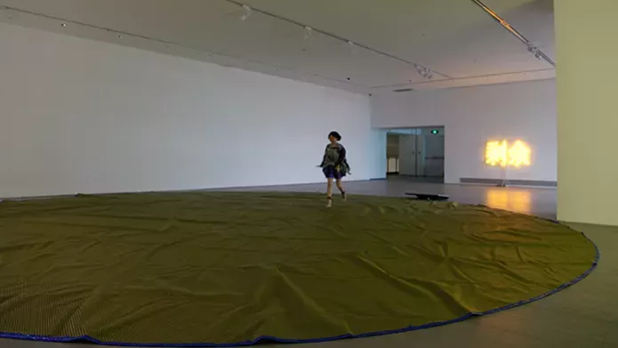 woman alone in gallery with circular fabric on floor