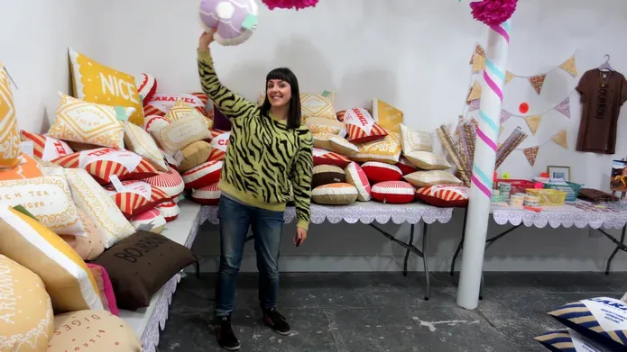 Nikki in a room with brightly coloured flowers and lots of cushions behind her