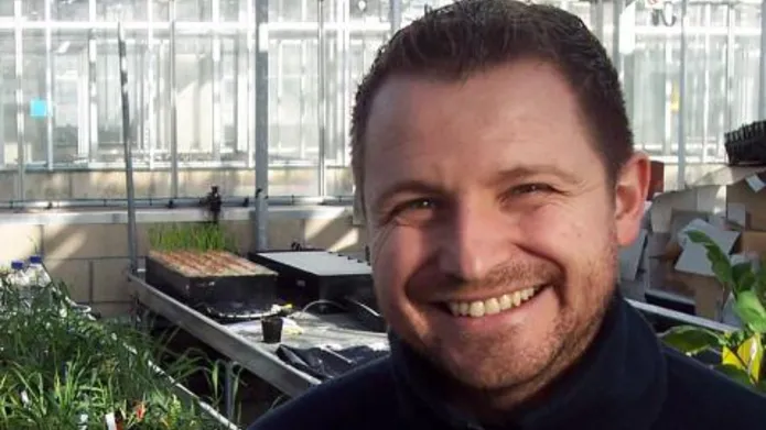 man in front of trays of plants