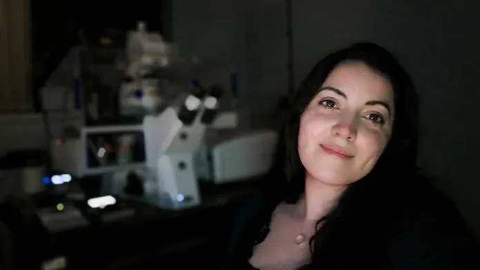 woman standing next to microscope in dark room