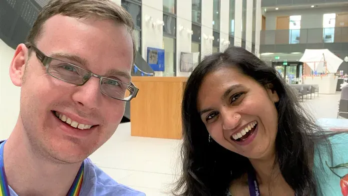 male and female scientist smiling together inside a reception area