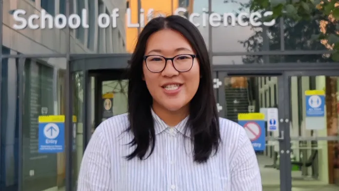 portrait of Vivien Shek in front of modern building, wearing a lab coat