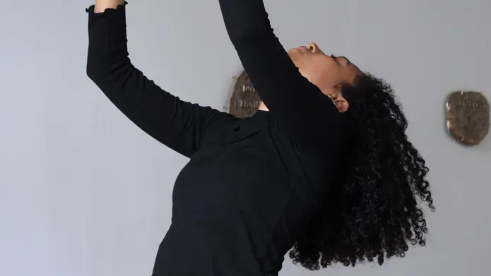 A women with her arms in the air and head back in an exhibition room