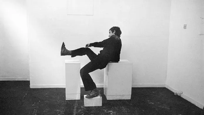Man sat on white boxes, raising one leg