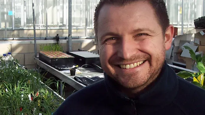 man standing in front of trays of plants