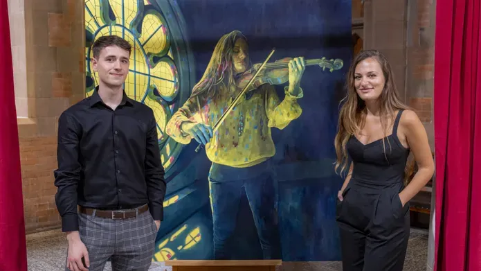 Artist Calum Stevenson stands beside musician Nicola Benedetti and a portrait of her that he painted