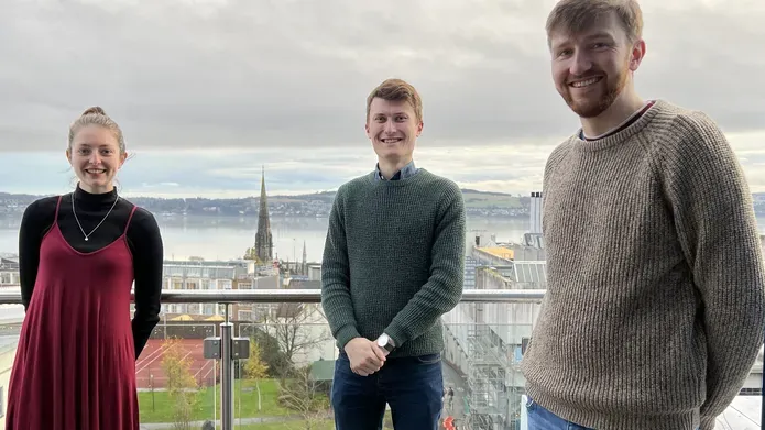 three students standing together outside overlooking Dundee