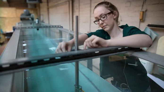 Girl working with water tank equipment in fluid mechanics lab.