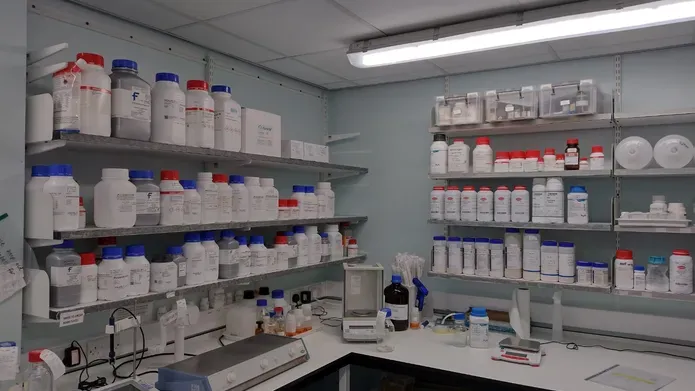 bottles of solutions on shelving in lab
