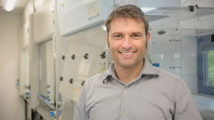 Alessio Ciulli standing in a lab with machines behind him