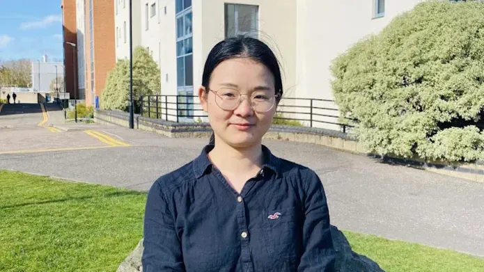 Xingui sits outside some buildings on the university campus.