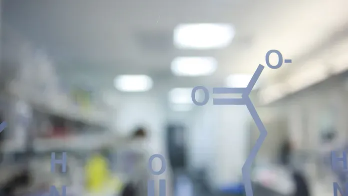 molecule painted on glass wall in front of a blurred out lab
