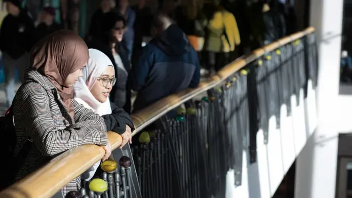 Two girls standing looking out over a balcony